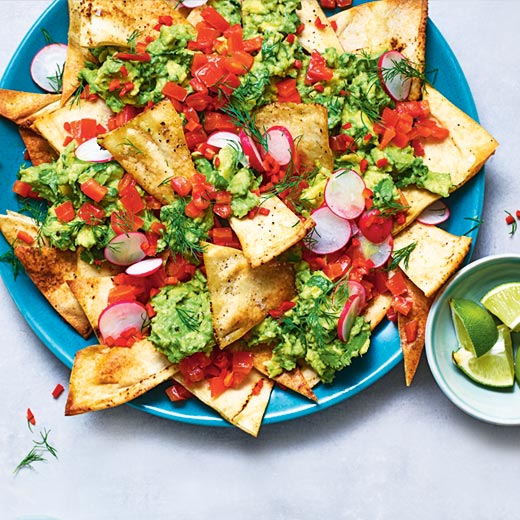 Homemade tortilla chips with crushed avocado and tomato salsa